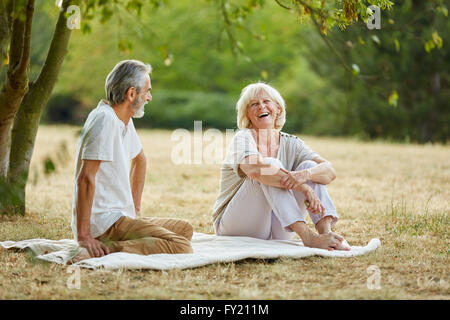 Happy senior citizens flirting in the park on a date in the park in summer Stock Photo