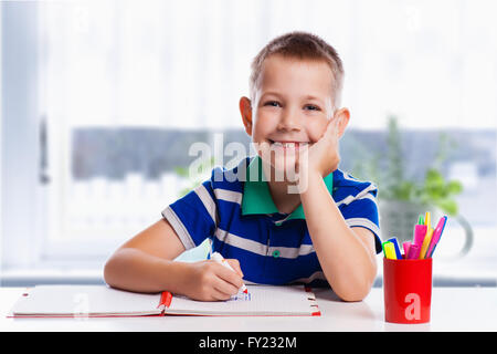 Cute schoolboy is writting isolated on a white background Stock Photo