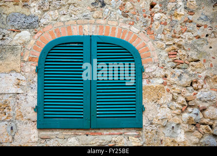 Blue shutters in a medieval stone wall in a Tuscan village in Italy. Eye catching colors and texture. Travel, architecture, etc. Stock Photo
