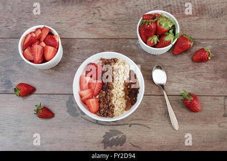 Healthy breakfast -yoghurt with oat flakes, raisins, strawberries, muesli. Fruit breakfast, wooden background Stock Photo
