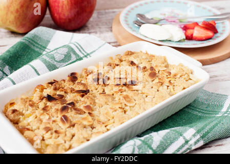 Apple crumble dessert with strawberries and vanilla cream on light rustic wooden background Stock Photo