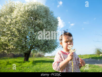 Happy child blowing dandelion outdoors in spring park Stock Photo