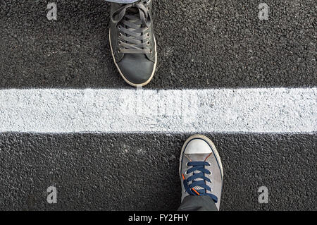 Top view of sneakers from above, standing next to white street lines. Selective focus Stock Photo