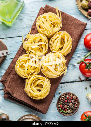 Pasta ingredients. Cherry-tomatoes, spaghetti pasta, rosemary and spices on the wooden table. Stock Photo