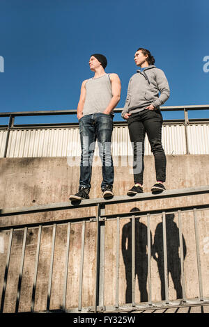 Casual and relaxed young man and woman balancing on rail in urban area, Sweden Stock Photo