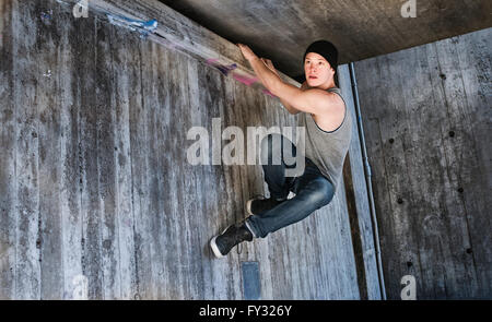 Young man hanging in a parkour move on concrete wall, Sweden Stock Photo