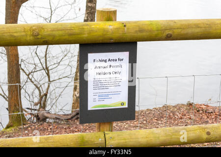 A sign on a fence displaying a 'fishing area for permit holders only' message at Black Park Lake, Wexham, Buckinghamshire, UK Stock Photo