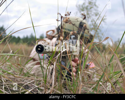 US Army soldier shooting his rifle while hiding in the grass Stock Photo