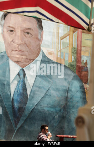 Man drinks coffee under Frank Rizzo mural, Italian Market, South Philadelphia, Pennsylvania, USA. Stock Photo