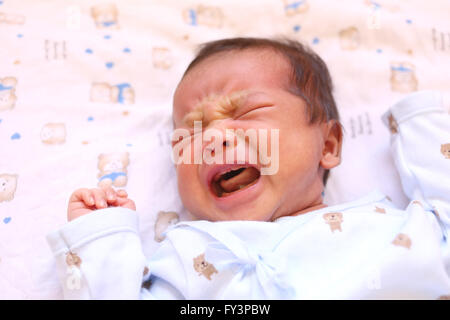 Newborn baby of asia crying on white bed and looked in a hungry milk. Stock Photo