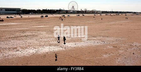 People play on the golden sands of Southport beach overlooked by the fairgrounds big wheel. Stock Photo