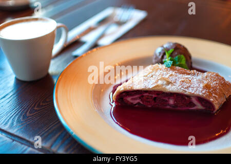Plate of cherry strudel and cup of coffee on a table Stock Photo