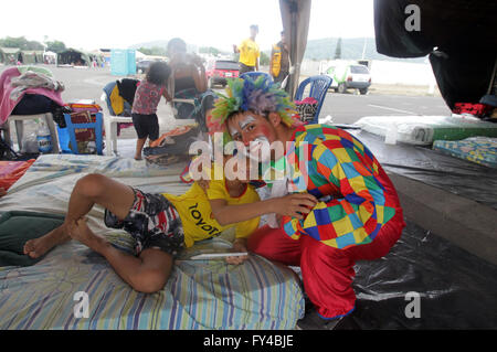 Portoviejo, Ecuador. 21st Apr, 2016. A clown cheers up a child in a shelter installed after the earthquake at Tamarindos airport in Portoviejo, Ecuador, on April 21, 2016. Ecuador's Prosecutor's Office said in its latest report that the death toll of the devastating earthquake has reached 577. At least 13 foreigners from various countries were among the dead. (Xinhua/Rong Hao) Stock Photo