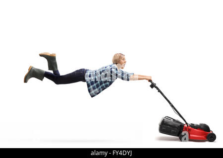 Young female gardener being pulled by a powerful lawnmower isolated on white background Stock Photo