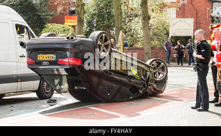 Car crash, black audi upside down with white van alongside, vote Labour election banner behind, police and fire men looking on Stock Photo