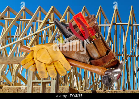 Carpenter tools, hammer, nails, screws, level, tape measure, screwdrivers, pliers and hacksaw with wood framed structure Stock Photo