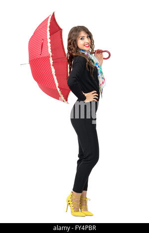 Side view of beauty fashion woman in black jumpsuit posing with red umbrella. Full body length portrait isolated on white Stock Photo