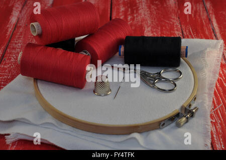 items for sewing and embroidery on the background of a red wooden table Stock Photo