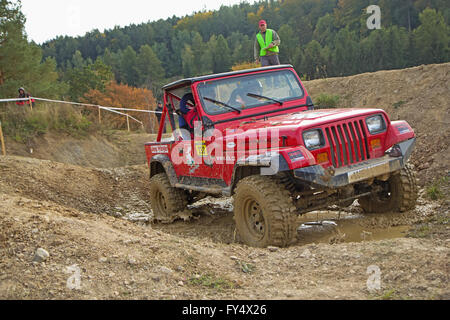 Red car is passing through  a puddle of mud on a trial race Stock Photo