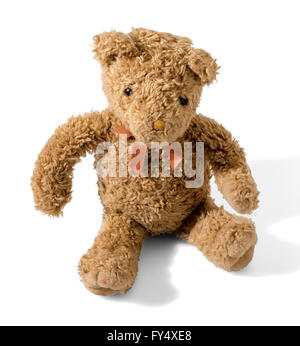Old plush brown teddy bear wearing a bow-tie sitting on a white background with shadow facing the camera Stock Photo
