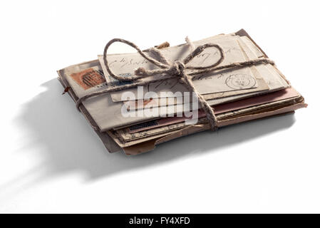 Pile of old vintage letters and envelopes with postmarks tied with string on a white background with shadow Stock Photo