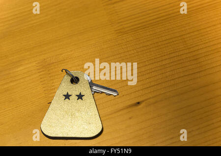 A key of a two stars hotel room is on a wooden table. Stock Photo