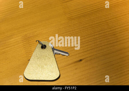 A key of a hotel room is on a wooden table. Stock Photo