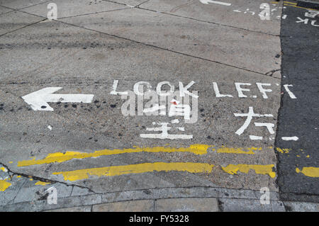 'Look Left' sign painted on the street in English and Chinese, informing pedestrians from which side road traffic is coming. Stock Photo