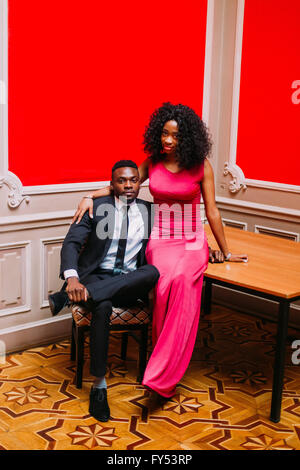 Portrait of handsome afro american businessman and beautiful african woman with red dress. Young couple hugging in the luxurious apartments Stock Photo