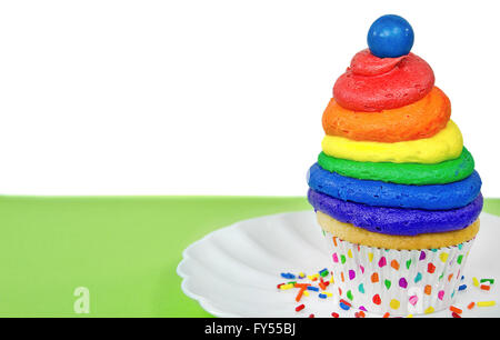 Rainbow frosting and blue gum ball on cupcake with colorful sprinkles. Stock Photo