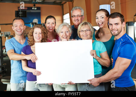 Big happy group holding empty white poster in fitness center Stock Photo