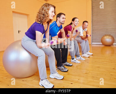Young people in back training class in a fitnesscenter with dumbbells Stock Photo
