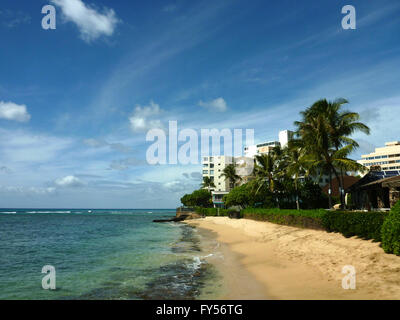 Makalei Beach with waves lapping, napakaa, lava rock wall and small hotels along the shore on a wonderful day in Oahu, Hawaii. Stock Photo