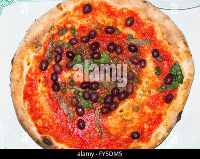 Genuine authentic Napoletana pizza with tomatoes, mozzarella, anchovies & olives, a classic Neapolitan recipe from Naples Italy Stock Photo