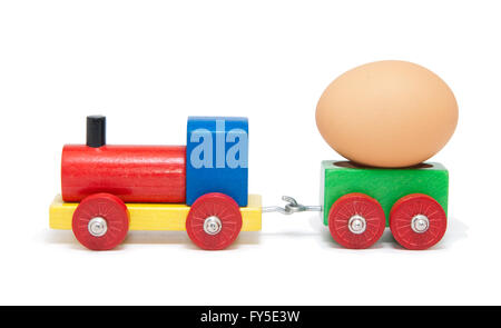 Colorful wooden model railway with an egg on a goods wagon, isolated Stock Photo