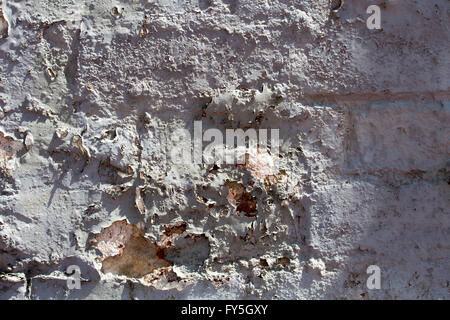 Weathered  eroded  peeling  grey painted  cement rendered  clay brick wall   exposed to the elements of wind and rain  is grungy Stock Photo