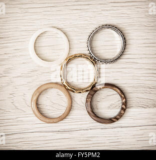 Women's rings arranged on the wooden background. Costume jewelry. Stock Photo