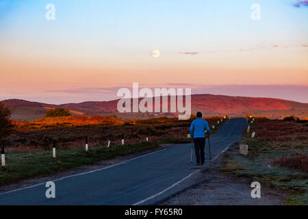 Flintshire, North Wales, UK Weather- Artic air pushes south over the UK leaving frost overnight, a walker enjoying sunrise and setting moon over Clwydian Hills on what could be a beautiful day, Flintshire, North Wales, UK. Stock Photo
