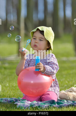 little girl with soap bubbles having fun outdoors Stock Photo