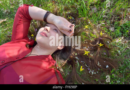 Portrait of young  girl  laying on grass with small flowers in her hair Stock Photo