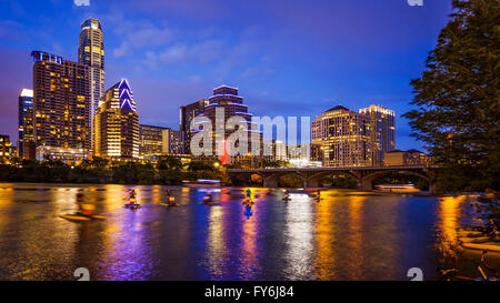 Austin, Texas downtown skyline at night on the Colorado River as unidentified tourists ride water bike's (All recognizable faces Stock Photo