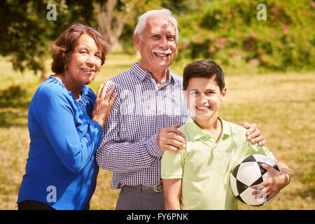 Grandparents spending time with grandson: Portrait of senior man and old woman playing football with grandchild in park. The old Stock Photo