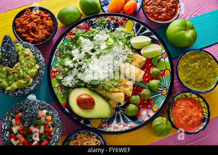 Green enchiladas Mexican food with guacamole and sauces on colorful table Stock Photo