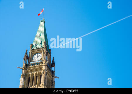 Peace Tower of Canadian Parliament Building in Ottawa, Canada with a plane over the blue sky and a white smoke trail Stock Photo