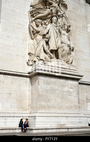 Visitors resting under the sculptures of Le Triomphe de 1810 on the facade of Arc de Triomphe.Paris France Stock Photo