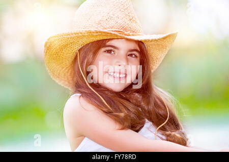 Portrait of а cute happy little girl wearing stylish straw hat, having fun outdoors, spending summer holidays Stock Photo