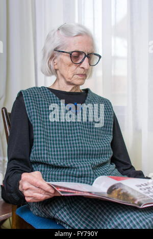 Ninety years old lady reading newspapers indoors Stock Photo