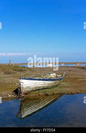 An abandoned small fishing boat on salt marshes at Brancaster Staithe, Norfolk, England, United Kingdom. Stock Photo