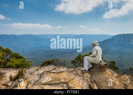 The imposing man in a hat sitting on the edge of a cliff 'Lincoln's Rock' admiring magnificent view of rocks and canyons Stock Photo
