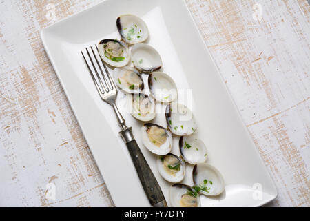 clams in white wine and parsley in rectangular plate on a rustic wooden table Stock Photo